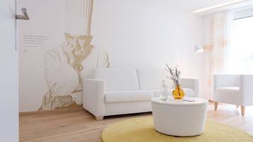 A modern living room with a white sofa, a round coffee table with a vase, and a large wall mural.