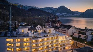 A multi-story hotel with a rooftop terrace, located near a lake with mountains in the background. - Neuro Campus Hotel by CERENEO PREVENTION (Vitznau)