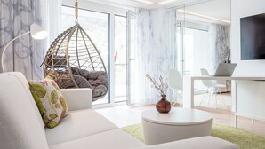 A modern living room with a hanging chair, a sofa with decorative pillows, a round coffee table, and a laptop on a desk. - Neuro Campus Hotel by CERENEO PREVENTION (Vitznau)