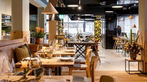 A restaurant interior with wooden tables, chairs, and a variety of table settings including wine glasses and candles. - Neuro Campus Hotel by CERENEO PREVENTION (Vitznau)