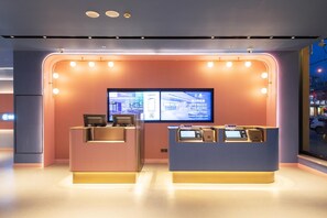 A modern reception area with two counters, a large digital screen, and a view of the street outside.