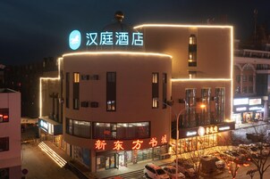 Un hotel con un letrero llamativo, una fachada moderna y un estacionamiento.