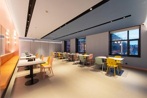 A modern conference room with tables and chairs, large windows, and a bench along the wall.