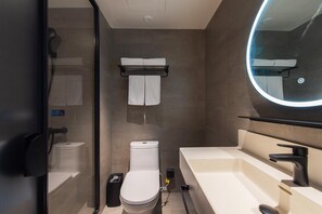 A modern bathroom with a toilet, bidet, and a large mirror.