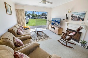 Een woonkamer met een bank, een schommelstoel, een televisie en een open haard.