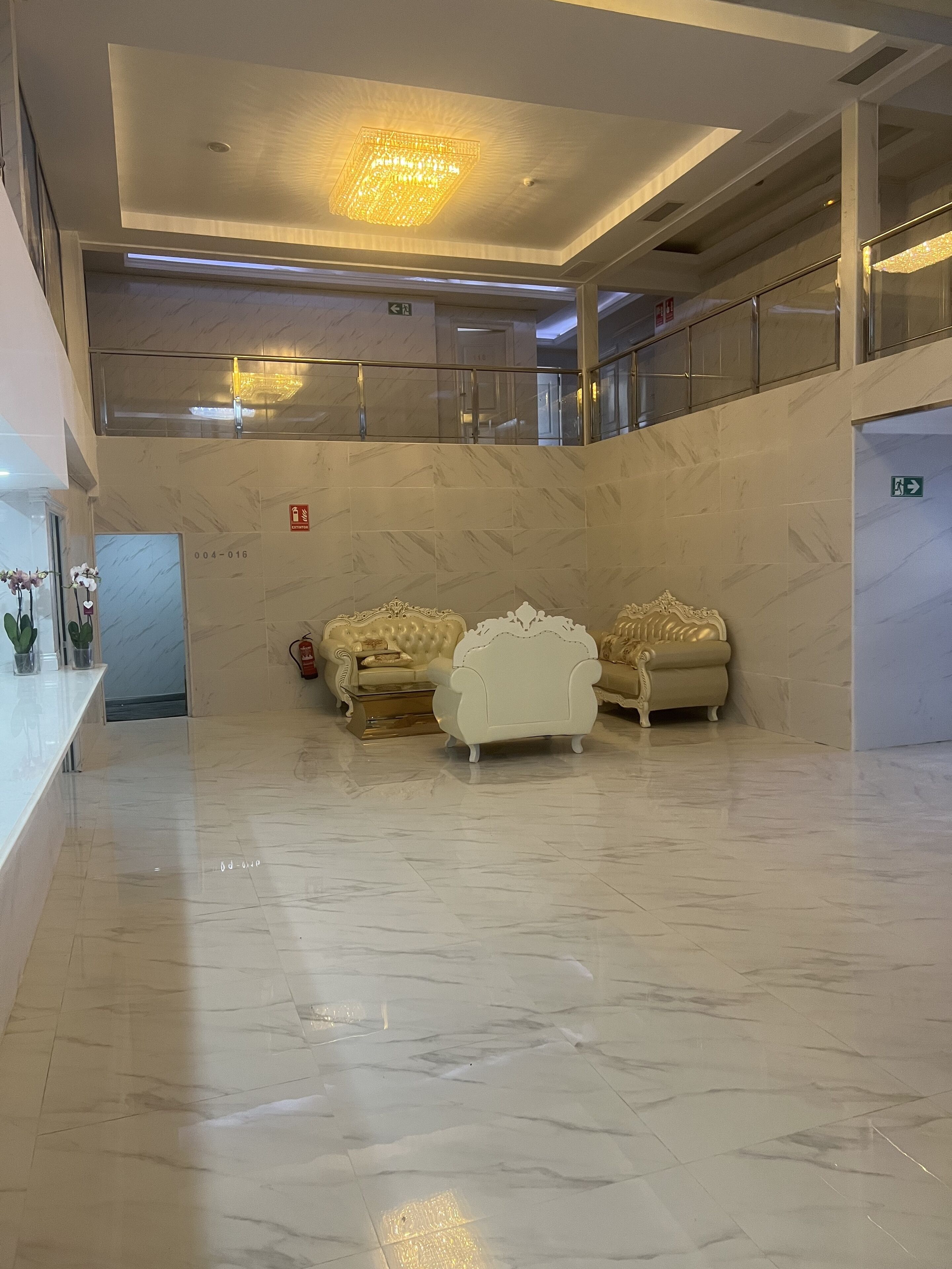 A spacious lobby with marble flooring, a grand chandelier, and elegant furniture.
