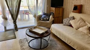 Ein gemütliches Wohnzimmer mit einer Couch, einem Couchtisch und einem Fernseher an einer Holzwand.