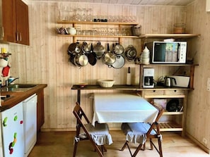 A compact kitchen with wooden cabinets, a microwave, a coffee maker, and a table with chairs. - Welcoming apartment with terrace A0314 (Cap-Ferret)