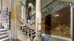 A staircase with ornate balustrades, a tiled floor, and a wall with peeling paint. - Real Apartments Klauzal II (Budapest)