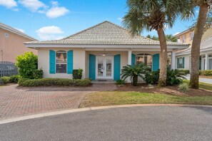 A two-story house with a tiled roof, teal shutters, and a number '33' on the front door.