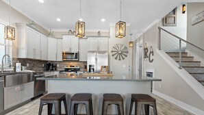Een moderne keuken met witte kasten, een centraal eiland met krukken en hanglampen.