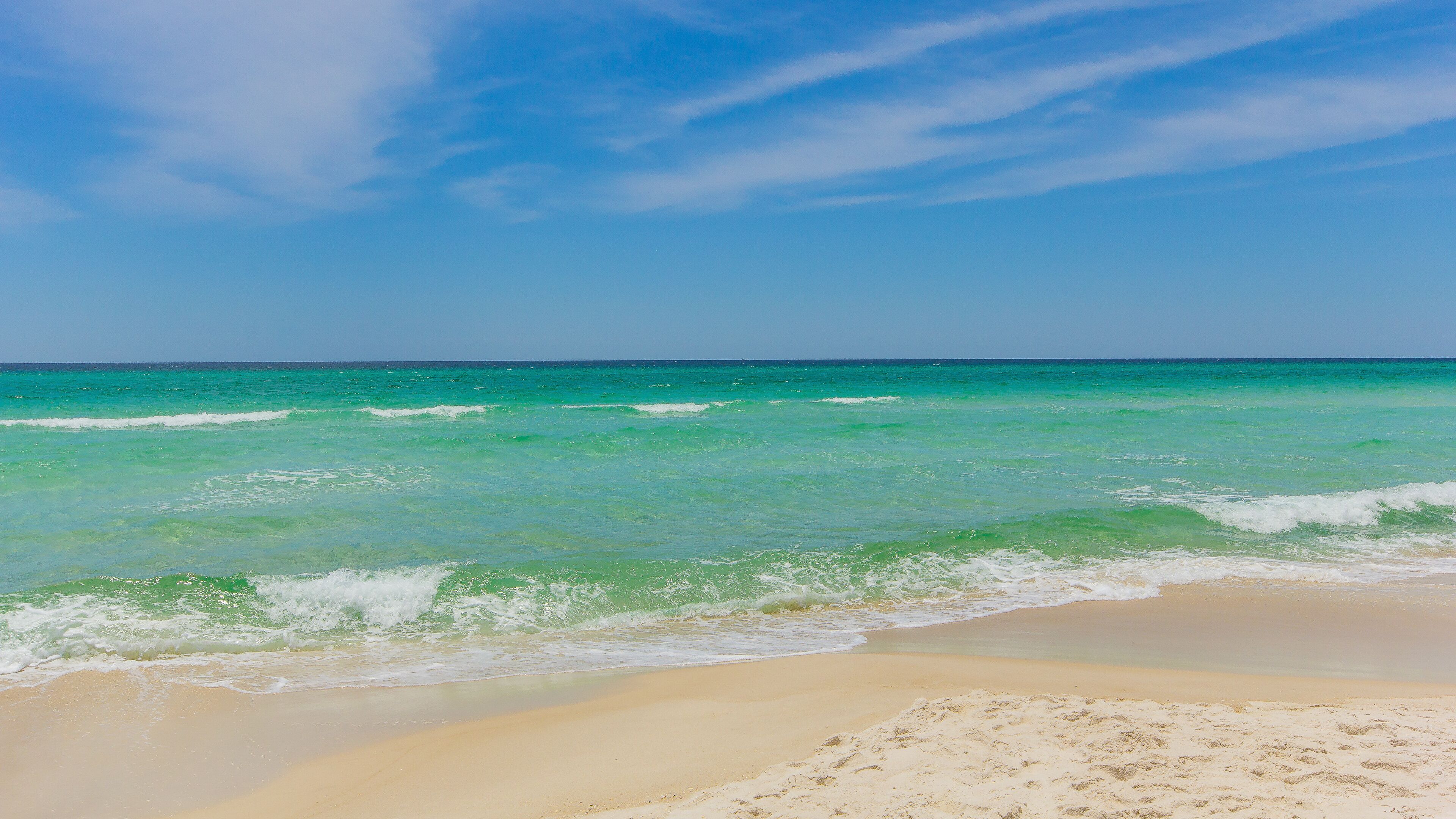 Ein Strand mit klarem türkisblauem Wasser und einem Sandufer.