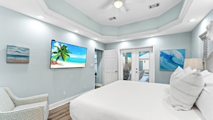 Ein Schlafzimmer mit einem großen Bett, einem Deckenventilator und einem Fernseher an der Wand.