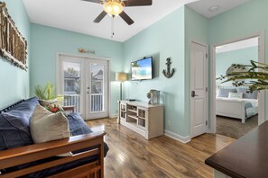 A room with a wooden bed, a white cabinet, a ceiling fan, and a door leading to another room.