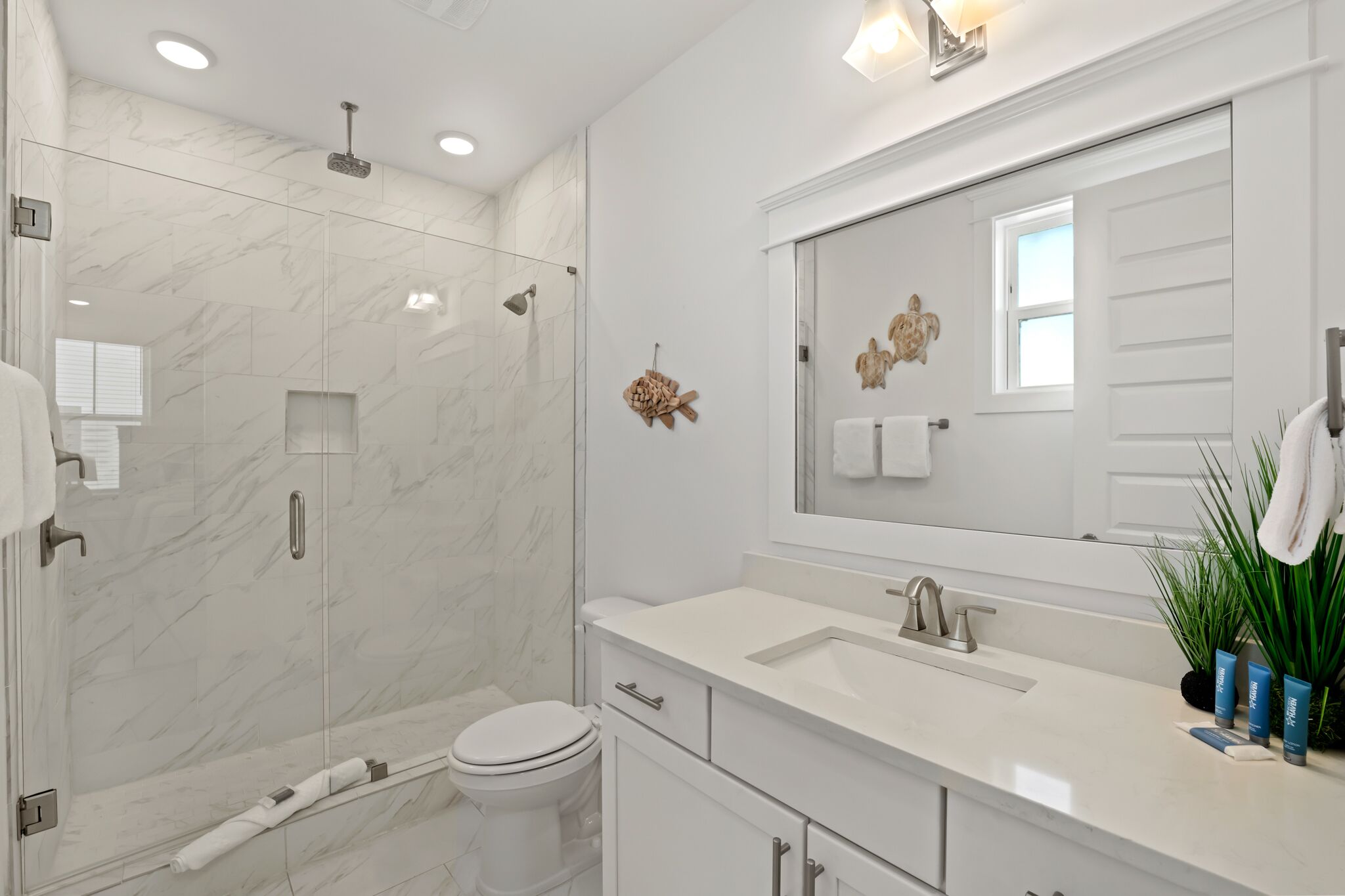 Une salle de bain moderne avec une douche à parois de verre, un lavabo blanc et un grand miroir.