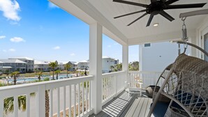 A covered outdoor area with a pool, white railings, and wicker furniture. - 30A Prominence ~ Golf Cart 6-Seat ~ Community Pool (Panama City Beach)