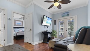 Un salon spacieux doté d’un grand téléviseur, d’un ventilateur de plafond et offrant une vue sur le balcon.