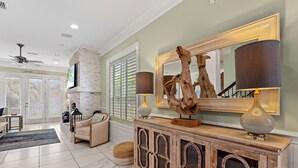 Un salon spacieux doté d’une cheminée, d’un grand miroir et d’une console agrémentée d’objets décoratifs.
