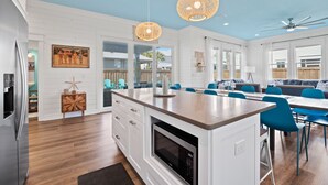Una cucina moderna con mobili bianchi, un'isola centrale e sedie blu.