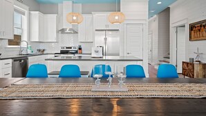 Una cucina moderna con mobili bianchi, un'isola centrale e sedie blu.