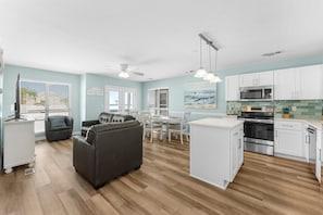 Enjoy meals in the dining area with a white table and chairs, or relax on the gray sofa.