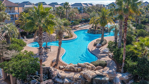 Een resort met een groot zwembad, palmbomen en uitzicht op hotelgebouwen.