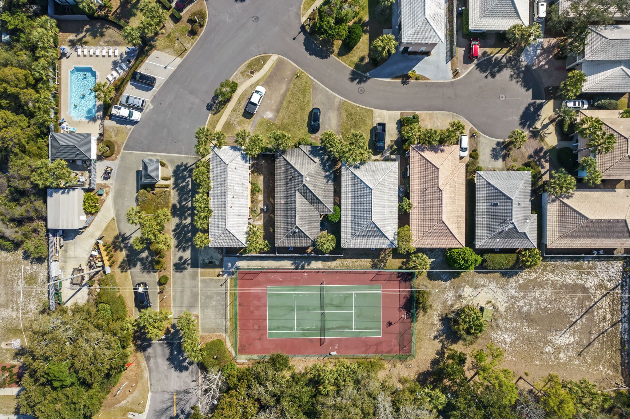 Oversigtsbillede af et boligområde med huse, tennisbane og swimmingpool.