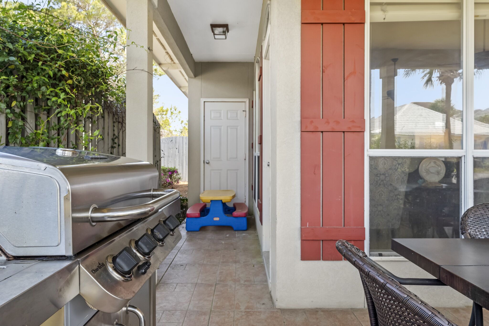 Une terrasse équipée d’un barbecue, d’une petite table et d’une porte donnant sur un espace intérieur.