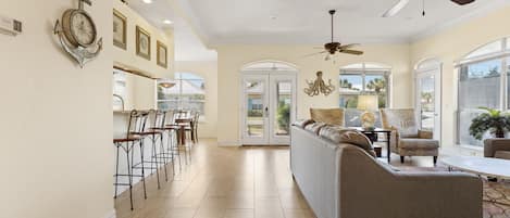 A spacious living area with a sofa, chairs, and a ceiling fan.