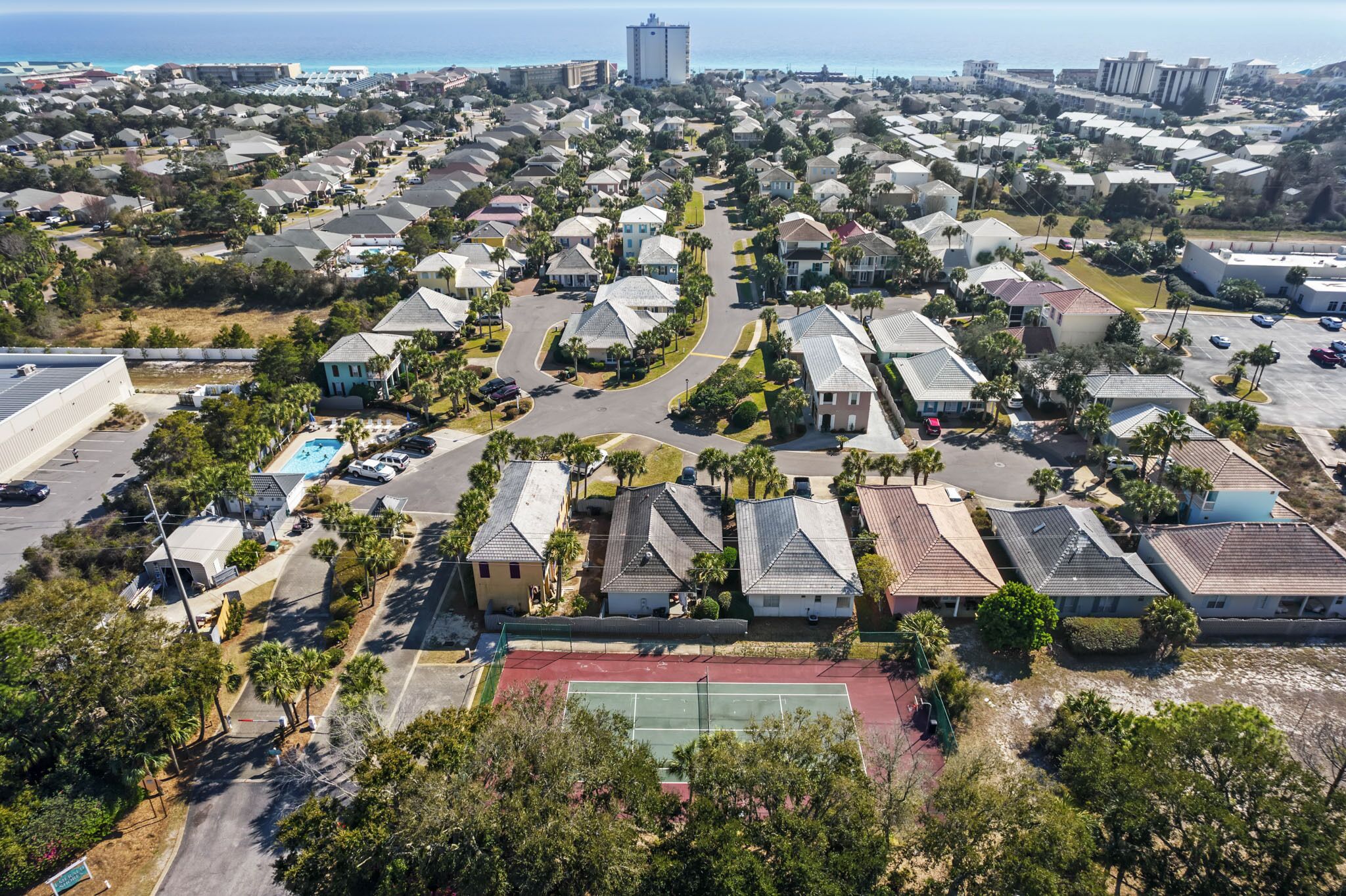 An aerial view of a residential area with houses, streets, and a tennis court.
