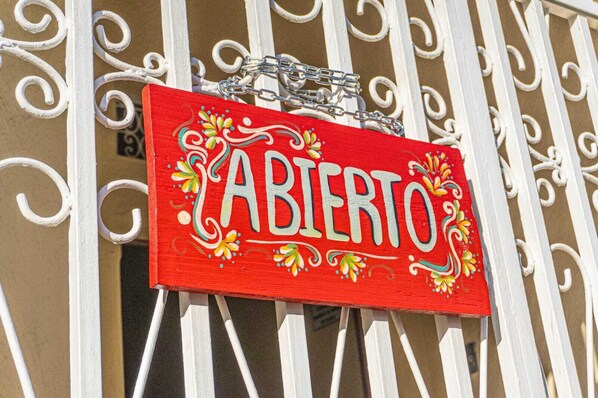 A red sign with the word 'ABIERTO' on a white metal gate.