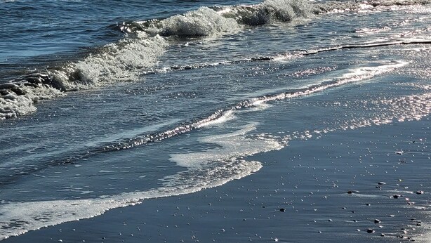 Een strand met golven die zachtjes op de kust spoelen.