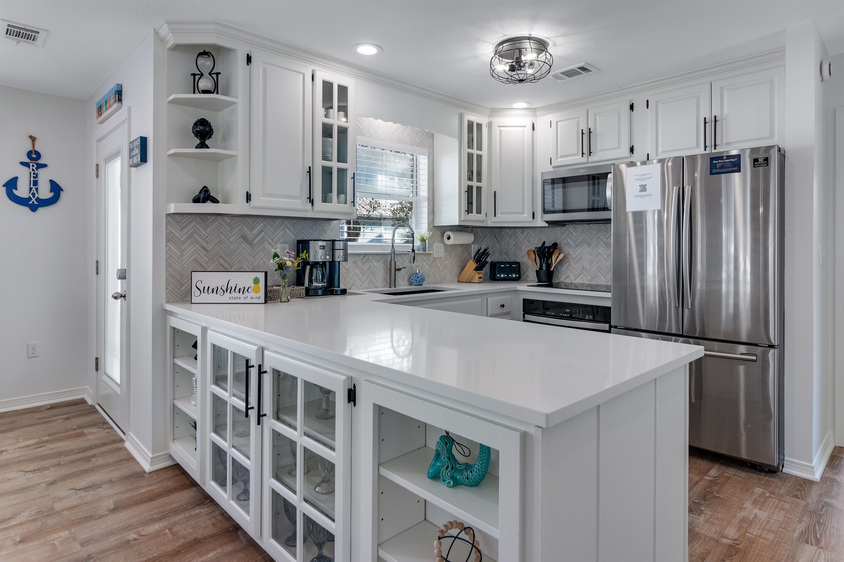A modern kitchen with white cabinetry, a stainless steel refrigerator, and a central island.