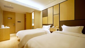 A hotel room with two beds, a wooden wardrobe, a bedside table with a phone, and a small desk with a coffee maker. - Ji Hotel (Nanjing)