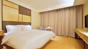 A hotel room with a large bed, a bedside table, a small round table, and a television on a stand. - Ji Hotel (Nanjing)