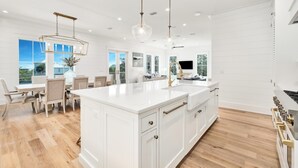 Un'ampia cucina con una grande isola, mobili bianchi e una moderna lampada a sospensione.