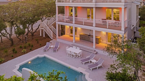 Una casa a più piani con piscina, area salotto esterna e una scalinata che conduce ai livelli superiori.