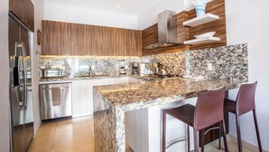 Eine moderne Küche mit Granit Arbeitsplatten, Edelstahlgeräten und Holzkorpussen.