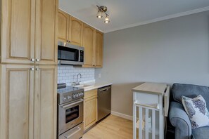 A compact kitchen with wooden cabinets, a microwave, an oven, and a dishwasher.