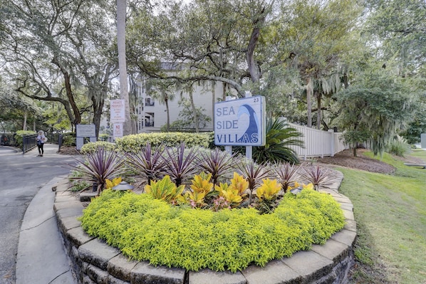 A sign for Sea Side Villas, surrounded by a landscaped garden with various plants.