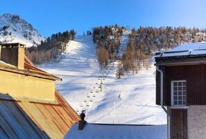 A ski resort with a chairlift, snow-covered slopes, and buildings with wooden roofs. - 20m from shops, 1st floor, tv, ski locker, 44m², Montgenèvre (Montgenèvre)