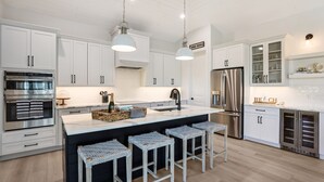 A modern kitchen with white cabinets, stainless steel appliances, and a central island with bar stools.