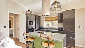 A modern kitchen with a central island, bar stools, stainless steel appliances, and pendant lighting. - Host & Stay | Eller Beck - The Cabin in the Woods (Whitby)