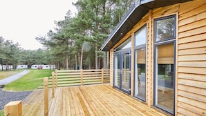A wooden deck with a glass door leading to a room, surrounded by a forest. - Host & Stay | Eller Beck - The Cabin in the Woods (Whitby)