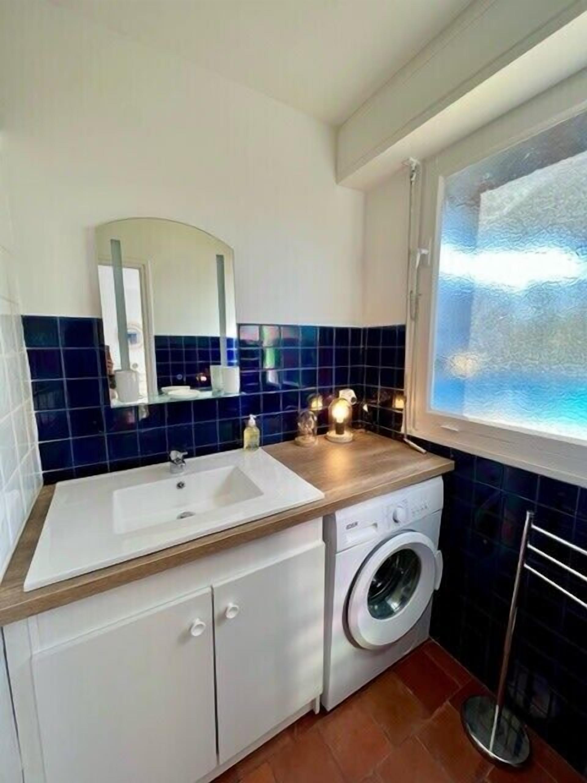 A compact bathroom with a sink, mirror, and washing machine.