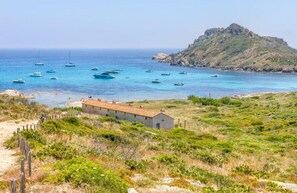 Un paisaje costero con barcos, un edificio y una colina.