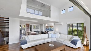 Un salón espacioso con un amplio sofá modular, una mesa de centro de madera y una escalera que conduce a un nivel superior.