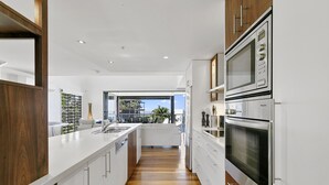 Una cocina moderna con armarios blancos, electrodomésticos de acero inoxidable y piso de madera.