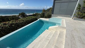 Una piscina con vista al océano y un edificio moderno.