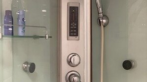 Moderni suihku, jossa on ohjauspaneeli, useita suihkupäitä ja lasinen suihkuseinä.